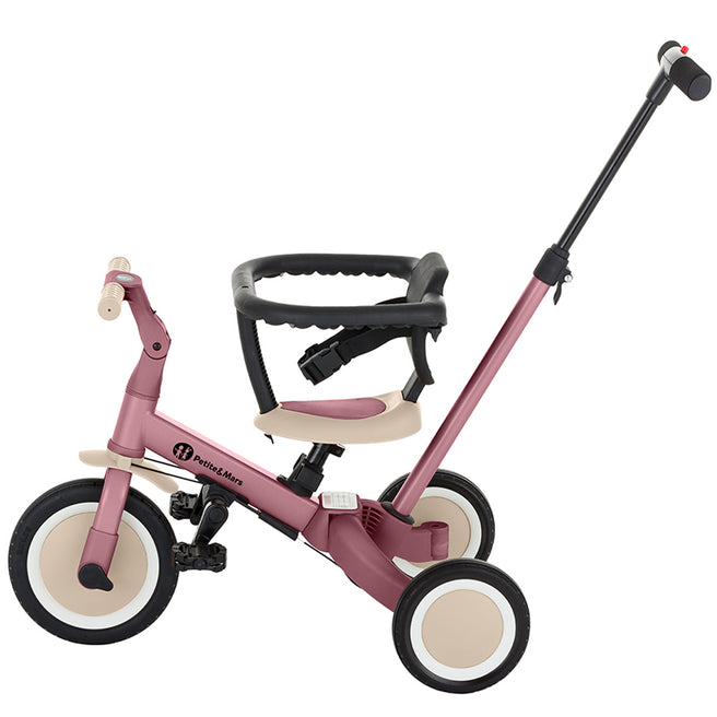 Petite&Mars 5-in-1 kinderfiets in dusty rose kleur, ingesteld als duw-driewieler met veiligheidsbeugel.