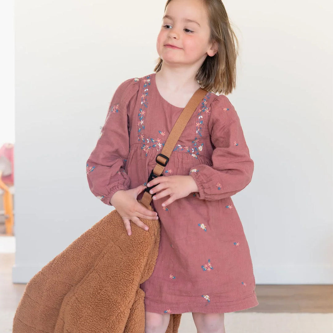 Een meisje draagt de play&go bruine teddy speelkleedtas over haar schouder.