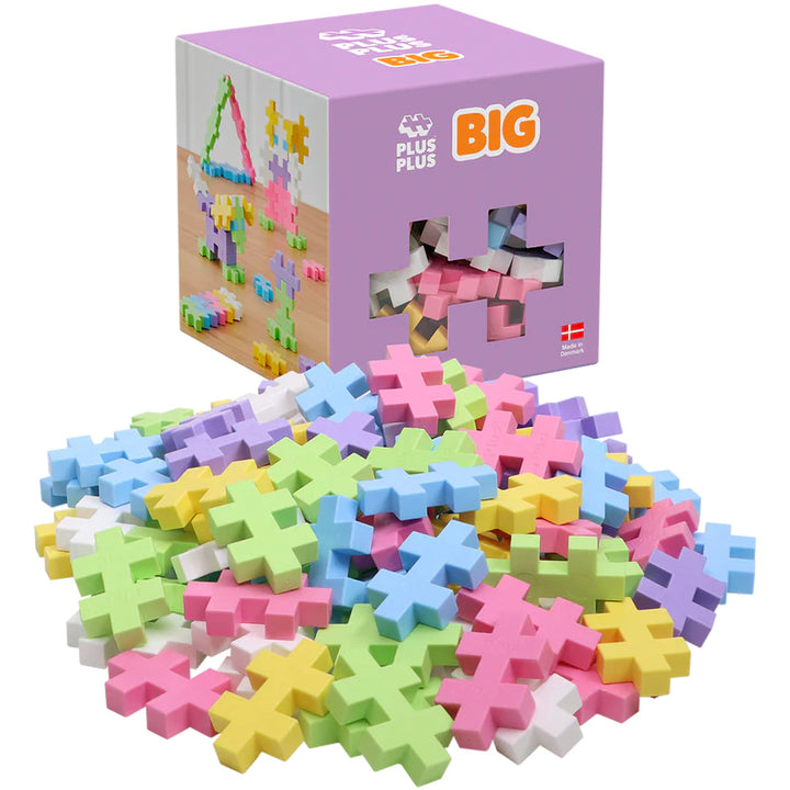 Plus-Plus BIG bouwblokken in pastelkleuren liggen voor de paarse verpakking.