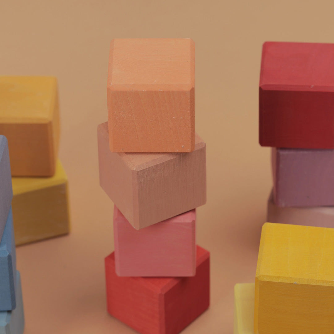 Meerdere stapels Raduga Grëz houten bouwblokken in diverse kleuren op een lichte ondergrond.
