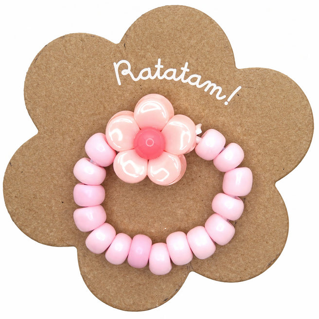 Ratatam kinderring met roze kralen en een roze bloem op een bloemvormige kartonnen verpakking.