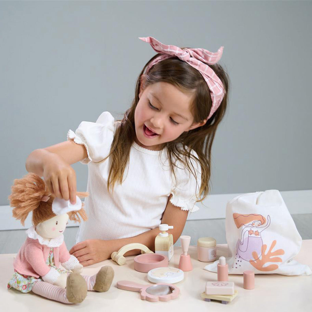 Een meisje speelt met de Tender Leaf Toys houten speelgoed wellness set en verzorgt een pop.