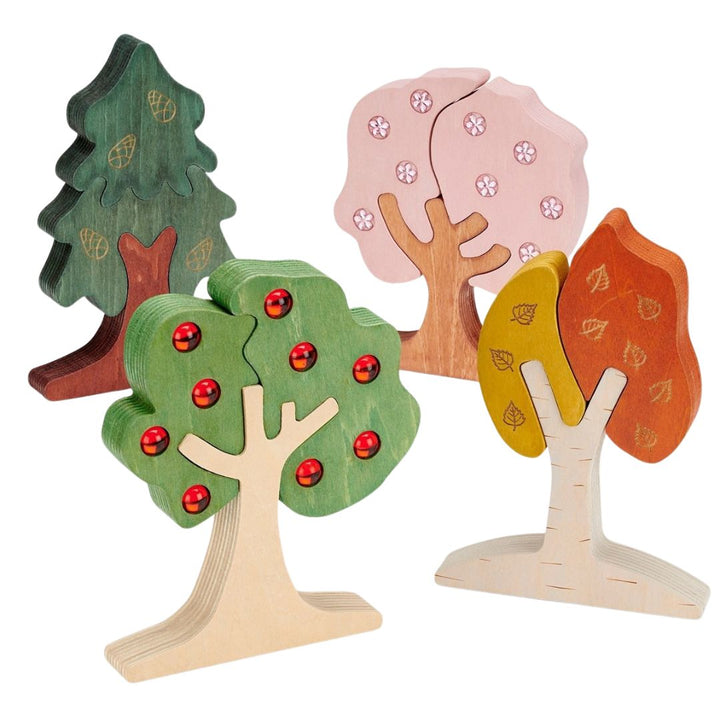 Vier Tickit houten bomen puzzels die de seizoenen voorstellen, staand op een witte achtergrond.